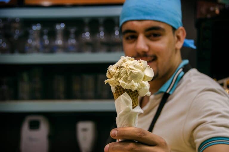 Man at shop handing over an ice-cream cone.